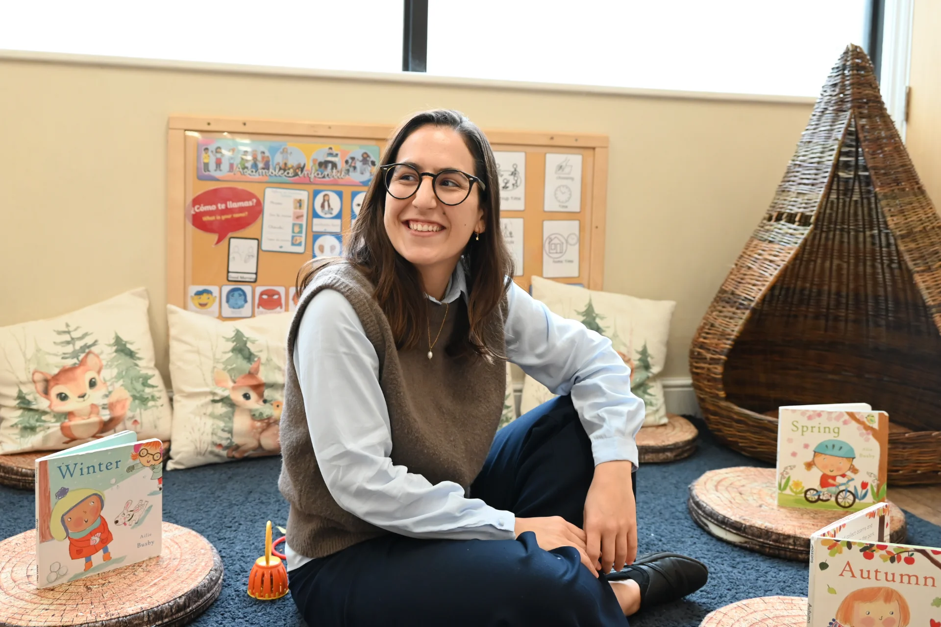 Smiling woman in nursery setting with children's books.